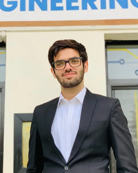 Syed Hamdan Hassan in a dark suit and glasses, outside an engineering building.