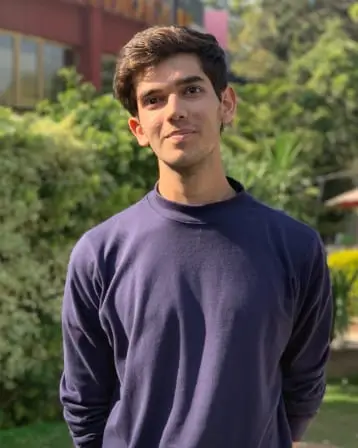 Syed Huzaifah Hassan in a navy jumper, outdoors in front of a hedge.