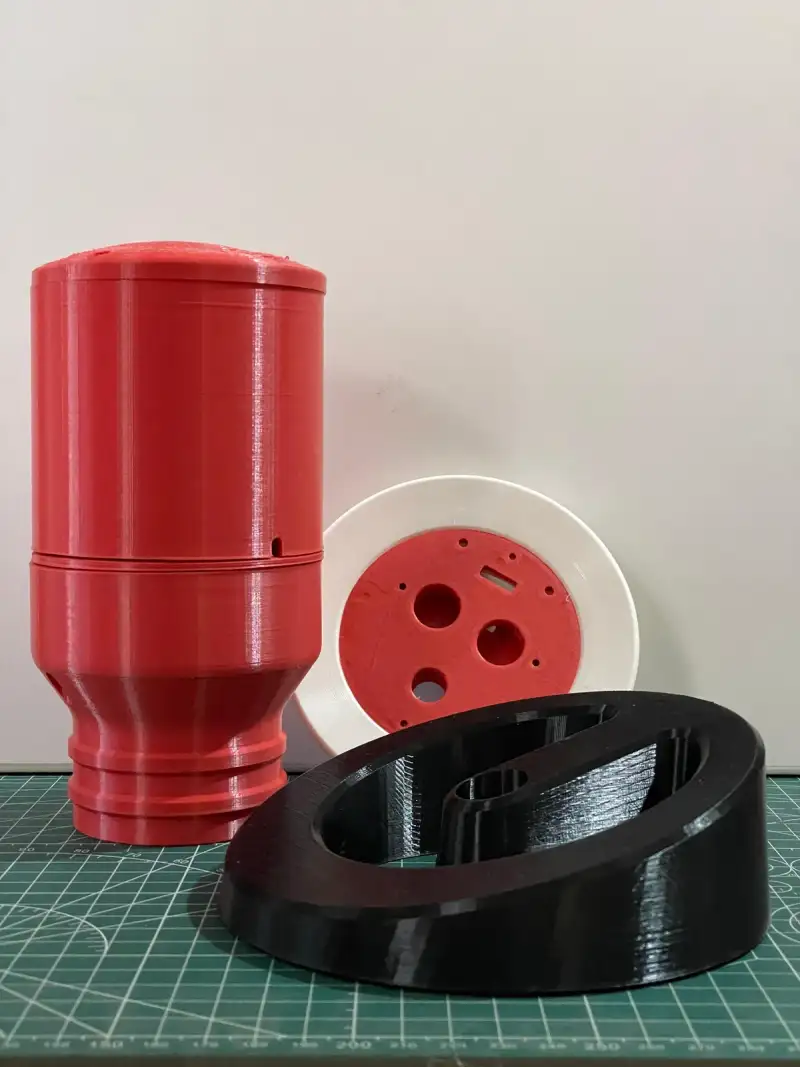 The printed prototype: a red pump casing, a white mounting ring and a black base.