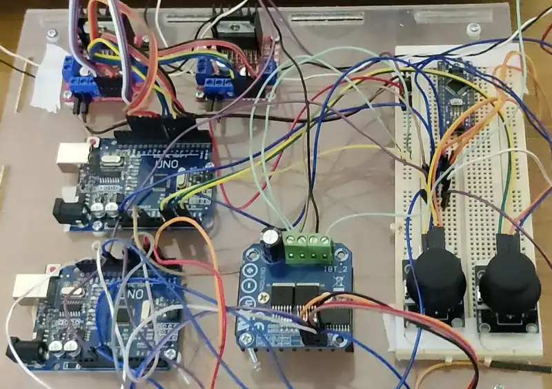 The bench rig: microcontroller boards, motor drivers and two joysticks wired on a board.